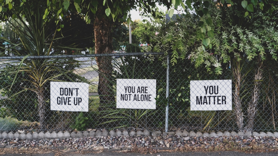 Signs on a fence that read "You are not alone"