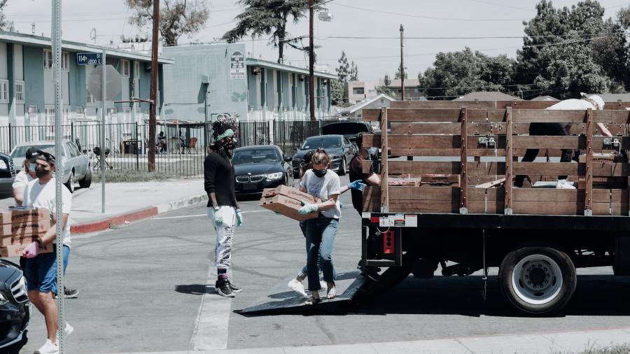 People in masks unloading packages of food from a truck