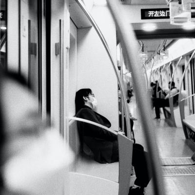 Masked person sitting in a subway car