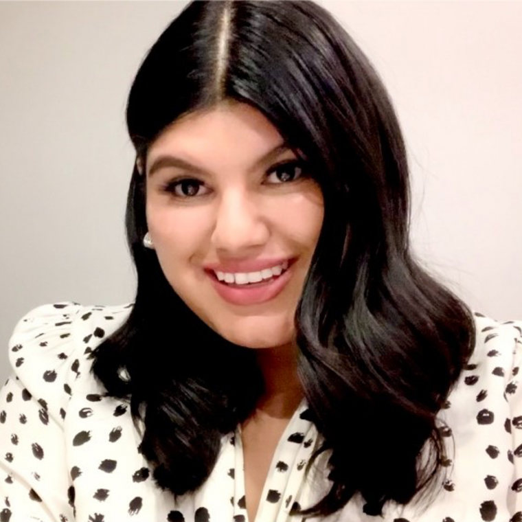 Giovanna Arenas wearing a polka dot shirt, smiling in front of a white wall
