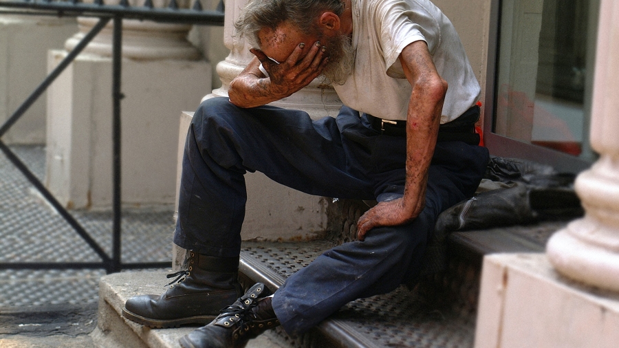 Senior sitting on a stoop with his head in his hand