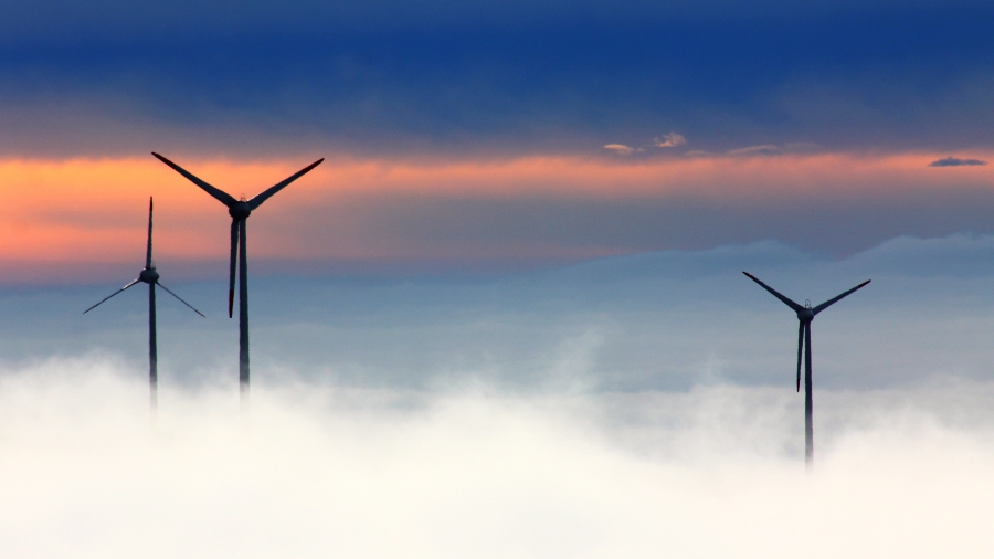 Windmills peeking through fog in front of a sunrise