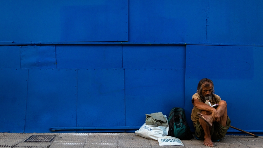 Person sitting on sidewalk