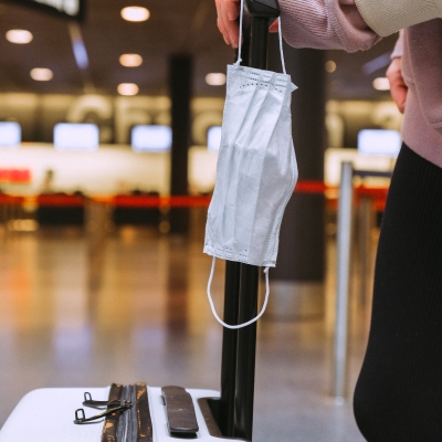 Person holding facemask and luggage