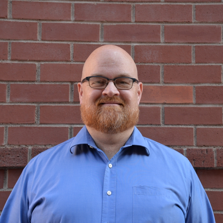 Ed Williams smiling in front of a brick wall