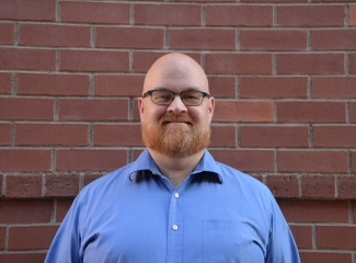 Ed Williams smiling in front of a brick wall